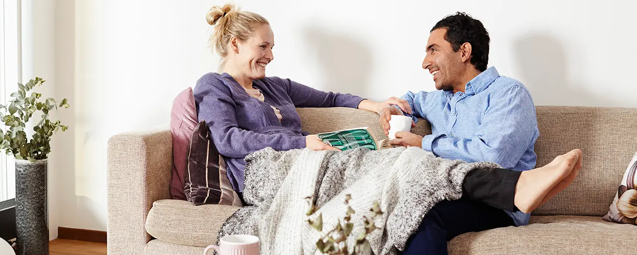 Två personer sitter i en soffa och har filt över sig