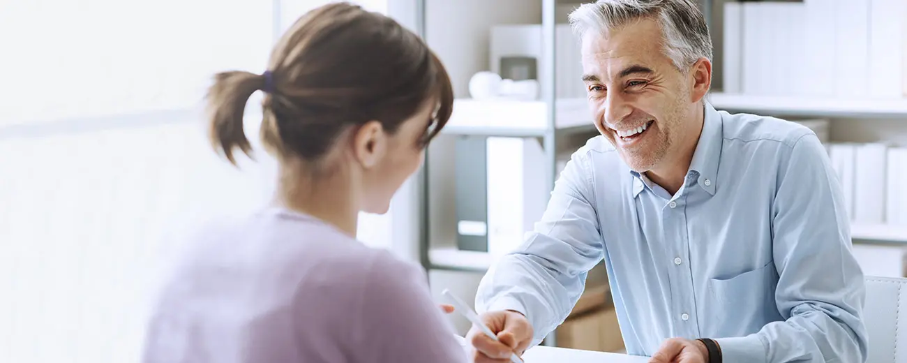 Två personer sitter mittemot varandra och pratar om ett avtal