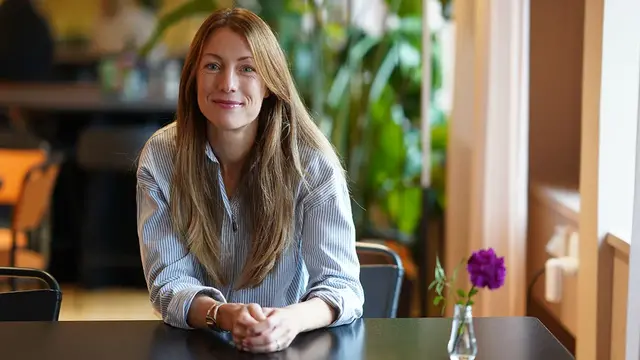 Emelie Bäckstadi, sjuksköterska, sitter vid ett bord och ler mot kameran