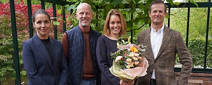 Fyra representanter från Euro Accidents ledning ler och tittar stolt in i kameran. En kvinna håller i en bukett.